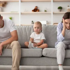 Zmęczeni rodzice siedzą na kanapie z dzieckiem pośrodku. Myślą o tym, jak uzyskać ulga na dzieci.