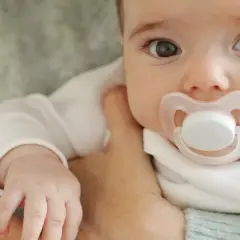 Malutkie dziecko z różowym smoczkiem w buzi. Czas pomyśleć, jak odzwyczaić dziecko od smoczka, by mogło swobodnie oddychać i rozwijać się.