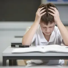 Chłopiec z rękami na głowie zastanawia się, ile punktów za egzamin ósmoklasisty z polskiego zdobędzie.