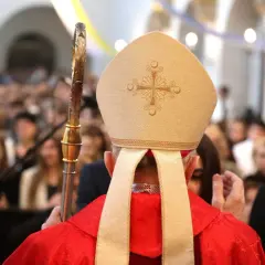 Biskup w mitrze i czerwonej szacie, trzymający pastorał, udziela sakramentu. Zastanawiasz się, ile trwa bierzmowanie?