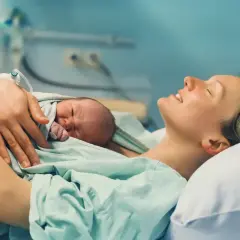 Szczęśliwa mama tuli noworodka. Może to Zuzanna lub Antoni, jedne z najpopularniejszych imion w Polsce.