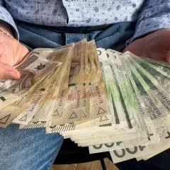 Ręce trzymające plik banknotów. Widać nominały 100, 200, 500 zł. To z pewnością więcej niż 1000 plus.