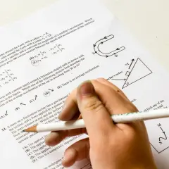 Dłoń z ołówkiem rozwiązuje test z fizyki. Pytanie 22 dotyczy satelitów, a od jakiej średniej jest 5? Odpowiedź D jest zaznaczona.