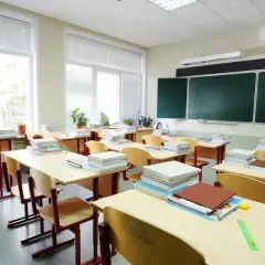 Puste ławki i stosy książek w klasie, jakby właśnie skończył się rok szkolny.