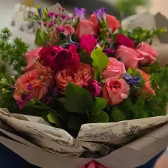Piękny bukiet różowych i czerwonych kwiatów, idealny jako kwiaty dla mamy. Delikatne róże, piwonie i ozdobne zielone gałązki tworzą romantyczną kompozycję.