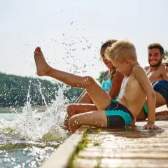 Rodzina pluska się w jeziorze, tworząc fontanny wody. To fajne miejsce na wakacje z dzieckiem w Polsce.
