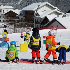 Dzieci na stoku, gotowe na ferie 2026. Wesołe kolorowe stroje narciarskie i śnieg wokół.