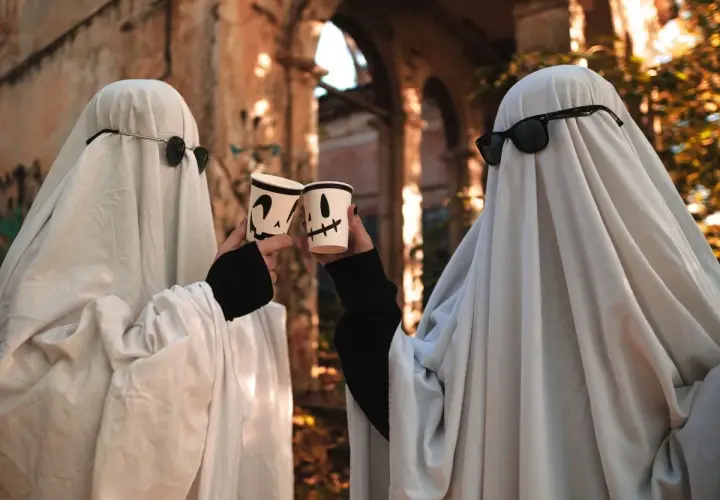 Dwa duchy w okularach przeciwsłonecznych wznoszą kubki z dyniami. Prosty strój, jak zrobić strój Hefajstosa, ale na Halloween!
