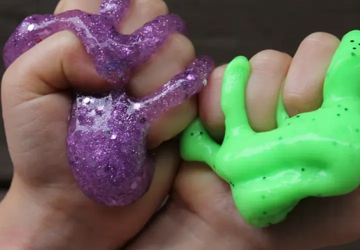 Dzieci bawią się fioletowym i zielonym slime'em, pokazując, jak zrobić slime.