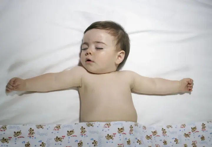 Śpiące dziecko z rozłożonymi rączkami. Choć obrazek nie sugeruje zespołu Turnera, warto pamiętać o jego istnieniu.
