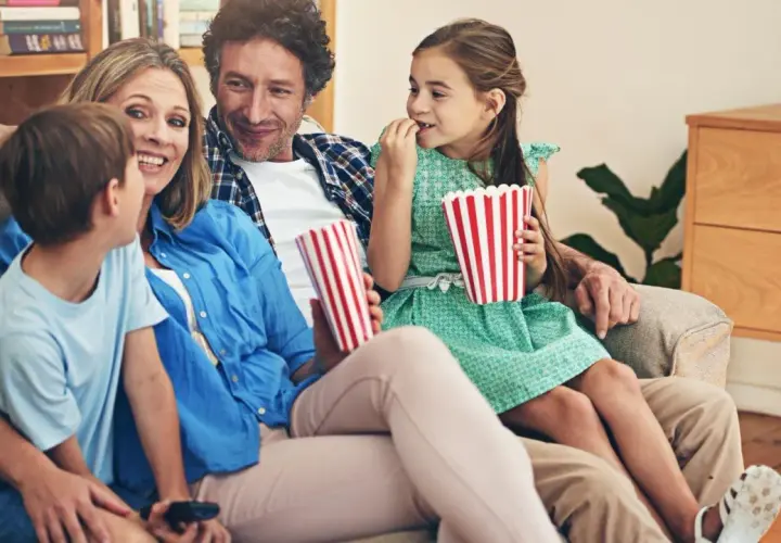 Rodzina ogląda filmy dla dzieci, zajadając popcorn.