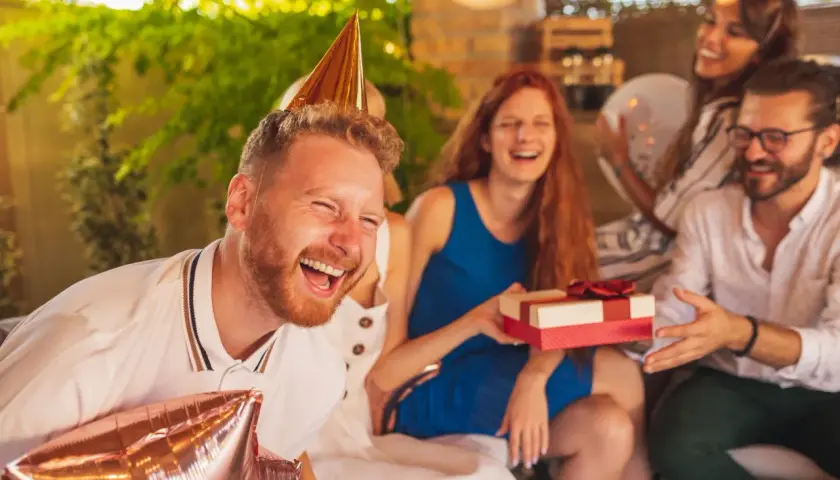 Impreza urodzinowa koleżanki w pełni! Wszyscy się śmieją, a on ma na głowie stożek i trzyma balony.