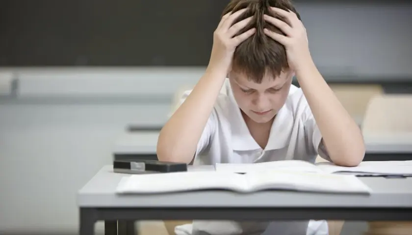 Chłopiec z rękami na głowie zastanawia się, ile punktów za egzamin ósmoklasisty z polskiego zdobędzie.
