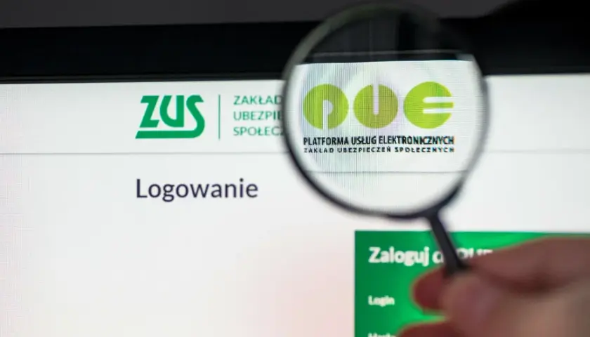 Lupa powiększa logo PUE ZUS, platformy usług elektronicznych. To miejsce, gdzie wielu Polaków, w tym osoby z 300 plus, loguje się do systemu.