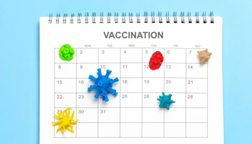 Kalendarz z napisem "VACCINATION" i kolorowymi modelami wirusów na dniach. Dtp szczepionka to ważny temat.