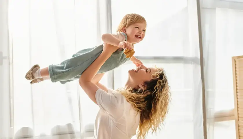Radosna mama podrzuca dziecko do góry. To są te chwile, dla których warto żyć, prawdziwe babciowe dla kogoś.