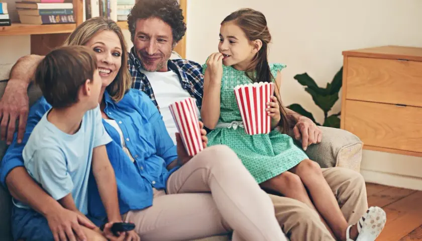 Rodzina ogląda filmy dla dzieci, zajadając popcorn.