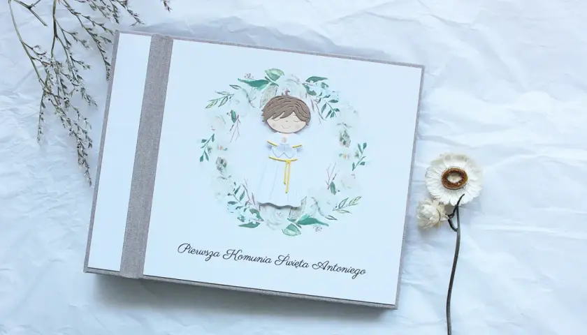 Album na pamiątkę Pierwszej Komunii Świętej dla chłopca. Urocza ozdoba z postacią dziecka w wianku. Idealny pomysł na prezent.