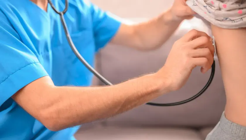 Lekarz osłuchuje klatkę piersiową dziecka, diagnozując zapalenie płuc.