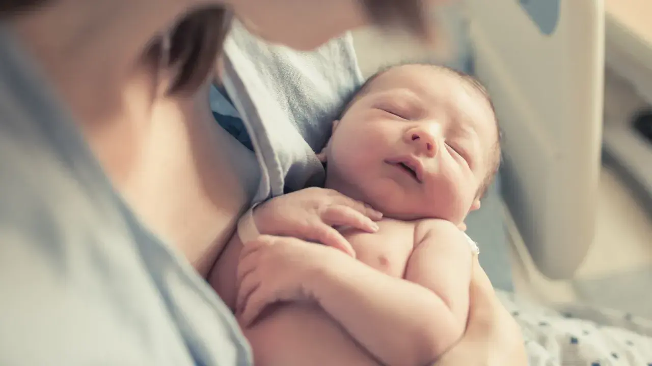 Śpiące maleństwo w ramionach mamy. Czy to będzie Zuzanna, czy może Jan? Poznaj najpopularniejsze imiona w Polsce.