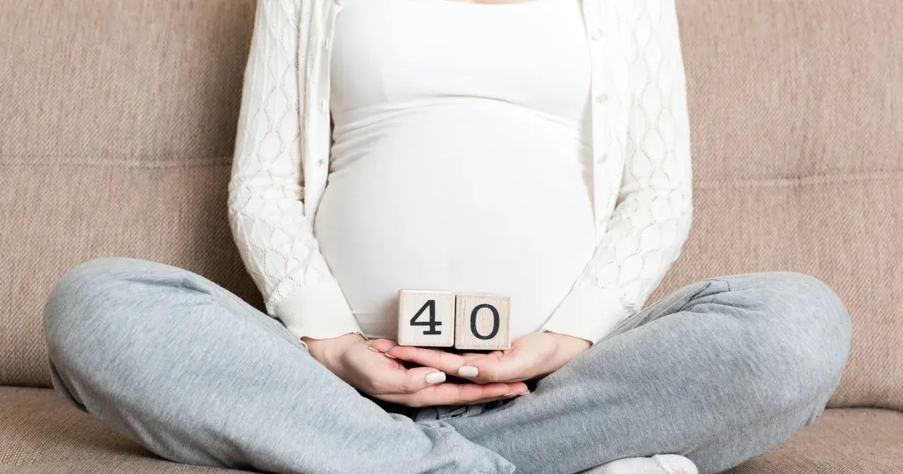 Ciąża trwa 40 tygodni. Kobieta w ciąży trzyma w dłoniach kostki z cyframi 4 i 0.