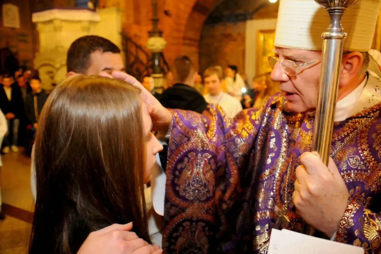 Biskup udziela sakramentu bierzmowania młodemu człowiekowi. W jakim wieku można przyjąć bierzmowanie? Zazwyczaj w wieku nastoletnim.