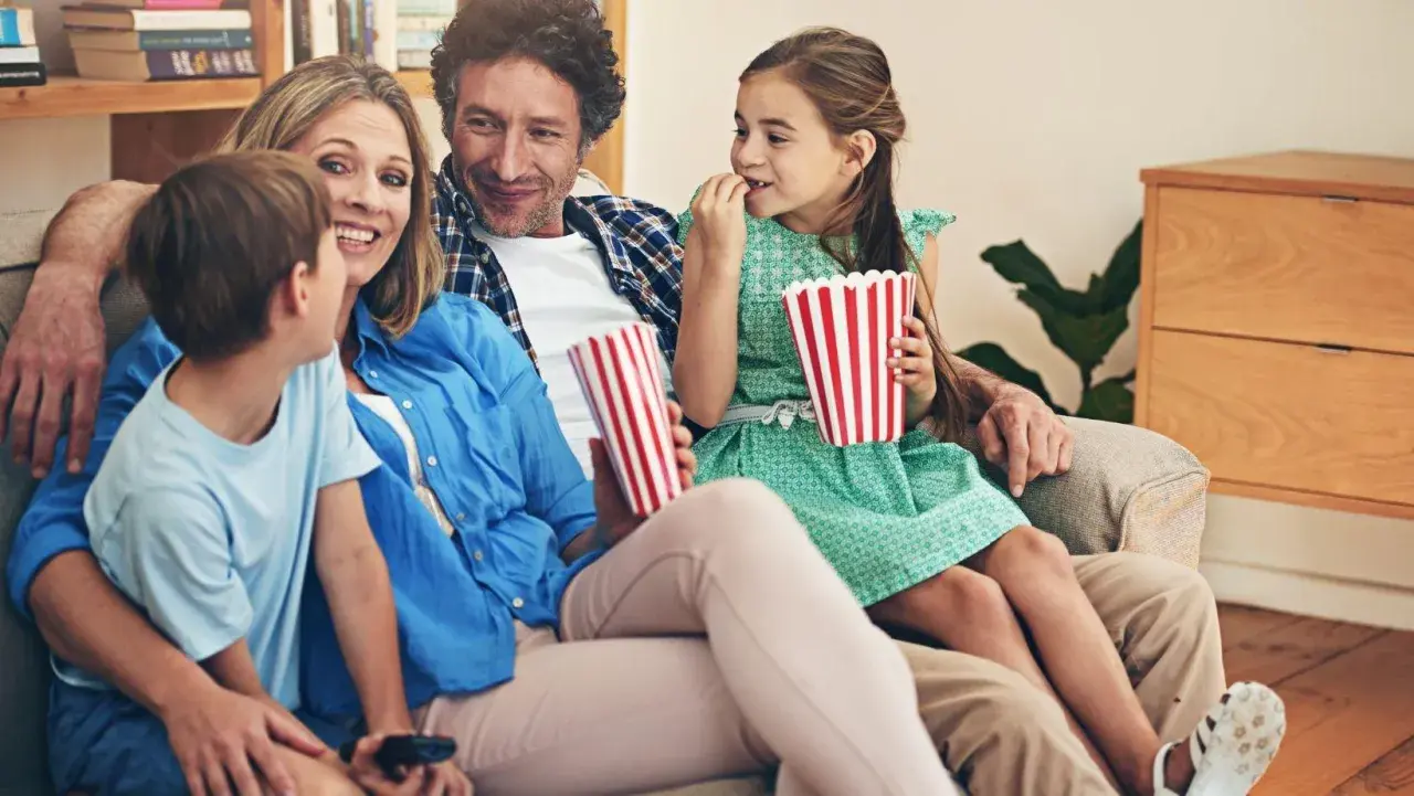 Rodzina ogląda filmy dla dzieci, zajadając popcorn.