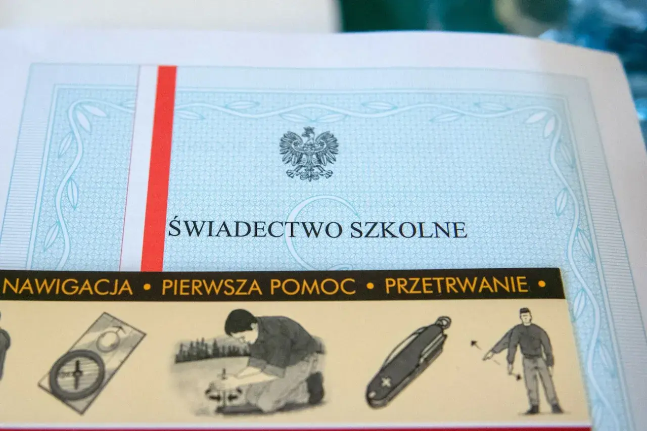Świadectwo szkolne z godłem Polski i paskiem w barwach narodowych. Poniżej widoczne grafiki: kompas, pomoc, nóż i przetrwanie.
