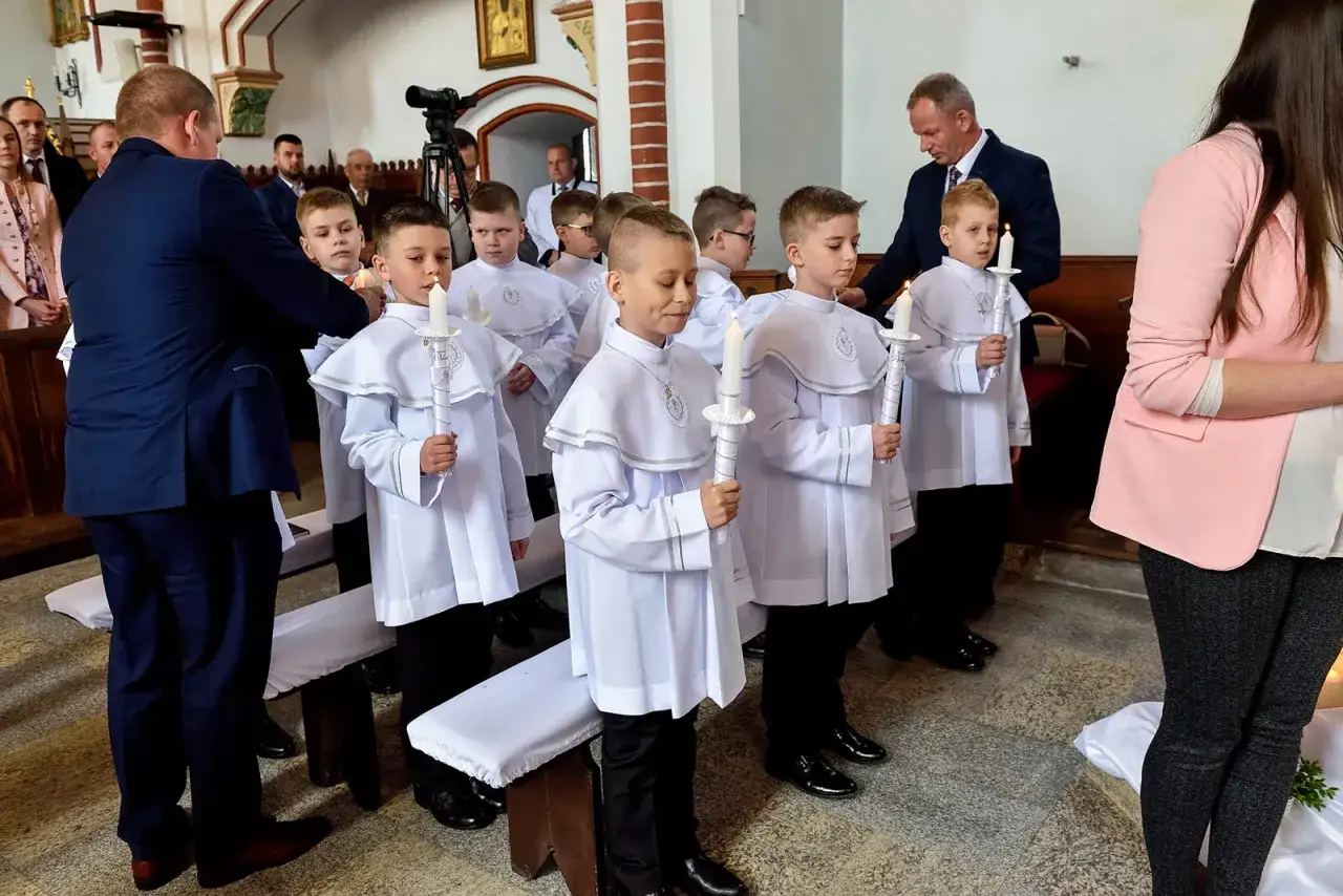 Chłopcy w białych albach, trzymający świece, przygotowują się do komunii. To ważny dzień, w której klasie odbędzie się uroczystość.