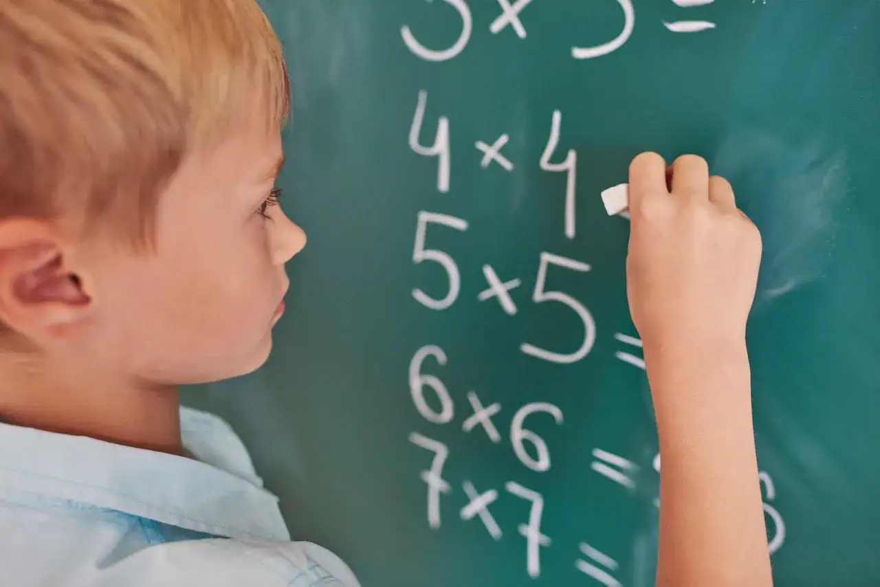 Chłopiec zmagający się z mnożeniem na tablicy. Czy to dyskalkulia, co to za trudność?
